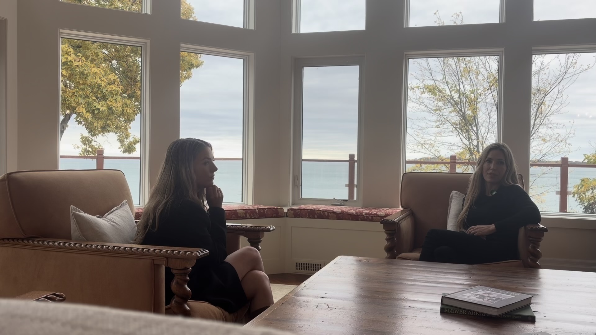 Anna and Andrea pause during their conversation in a bright room overlooking the water.