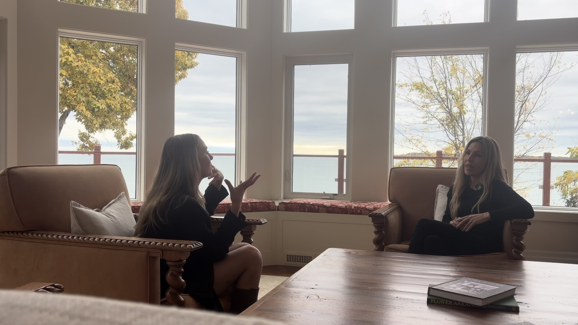 Anna talks with home stager Andrea Richards beside a lakeside window.